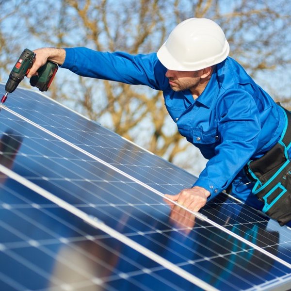 Monteur montiert Solarmodule mit Akkuschrauber