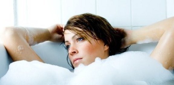 Frau entspannt in einer Badewanne voller Schaum
