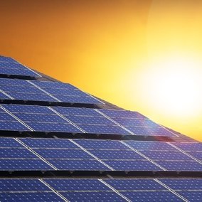 Hände formen ein Haus vor Wiese und blauem Himmel