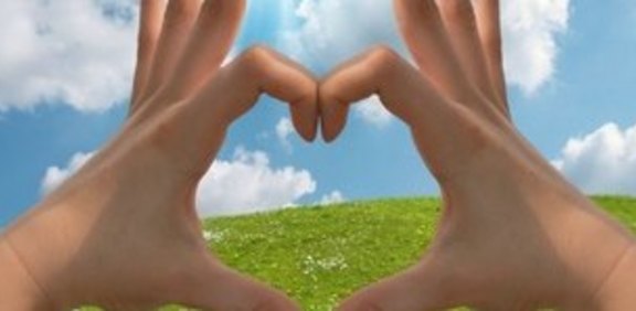 ChatGPT:  Hände formen ein Haus vor Wiese und Himmel.