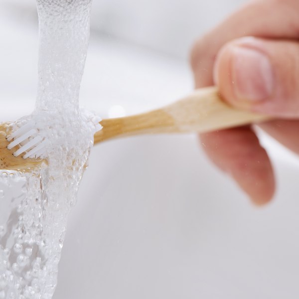 Hand spült Zahnbürste unter fließendem Wasser ab