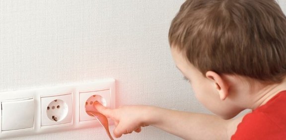 Kind greift in Steckdose
