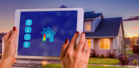 Tablet steuert Smart Home vor Wohnhaus