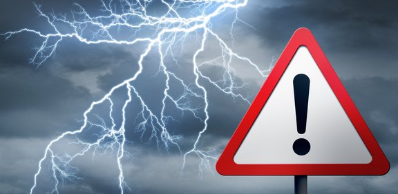 Gewitterhimmel mit Blitzen und Warnschild mit Ausrufezeichen